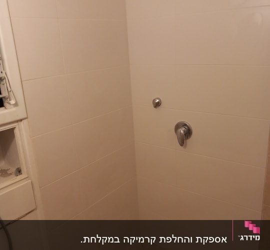 קיר אריחים לבנים עם ברז ומערכת ניקוז